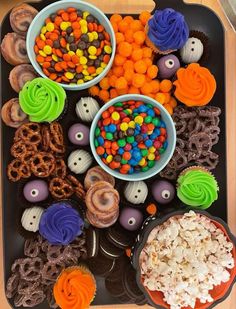 a tray filled with lots of different types of candy and cupcakes on top of it