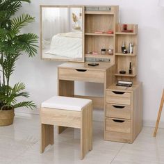 a wooden desk with a mirror, stool and shelf on the floor next to a potted plant