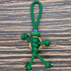 a small green toy with a turtle on it's back hanging from a rope