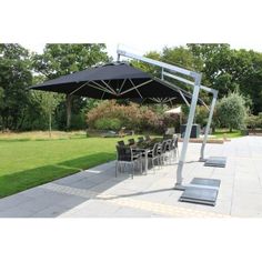 an outdoor dining area with tables, chairs and umbrellas on the grass in front of trees