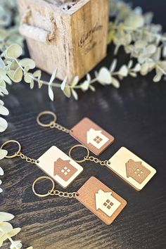 four wooden key chains sitting on top of a table next to flowers and a box