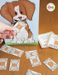 a person is playing with an animal themed card game on a wooden table next to other cards