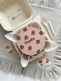 a pink cake with hearts on it sitting in a box next to utensils