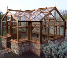 a wooden greenhouse built into the side of a brick building with glass walls and roof