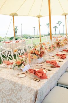 the tables are set with orange napkins and place settings for an outdoor wedding reception