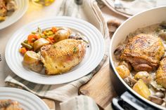 two white plates with chicken, potatoes and carrots on them next to a pot of stew