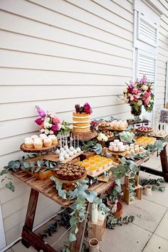 a table with cakes and cupcakes on it in front of a white house