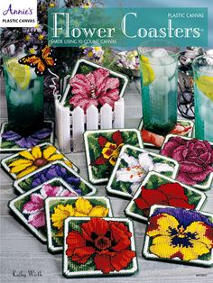 cross stitch coasters with flowers on them in front of two green drinks and vases