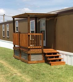 a mobile home with stairs leading up to the front door and steps down to the porch