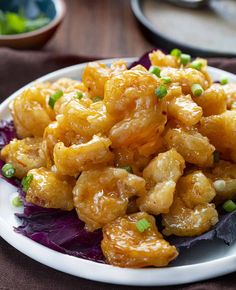 a white plate topped with fried food on top of lettuce and garnished with green onions