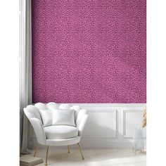 a white chair sitting in front of a pink wallpapered room with a large window