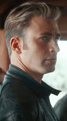 a close up of a person wearing a leather jacket and looking off into the distance