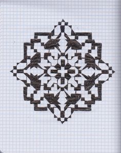 an intricately designed piece of paper on top of a sheet of graph paper with black ink