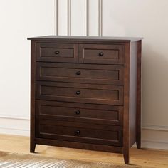 a wooden dresser sitting on top of a hard wood floor next to a white wall