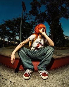 a woman with red hair sitting on the curb