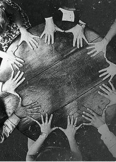 a group of people sitting around a table with their hands on top of each other