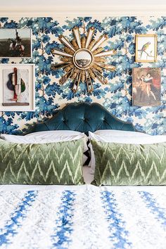 a bedroom with blue and white wallpaper, green bedding and pictures on the wall