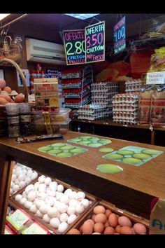 eggs are on display in a store with other food items behind the counter and signs