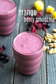 two glasses filled with smoothie next to berries and nuts