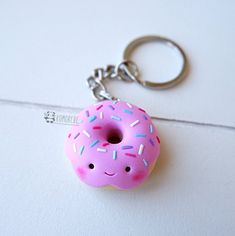 a pink doughnut with sprinkles on it sitting on a white surface