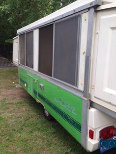 a green and white trailer parked on top of a grass covered field