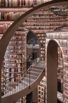 a spiral staircase in front of a bookshelf filled with lots of book shelves