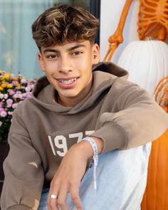 a young man sitting on the ground with his hand on his hip and smiling at the camera