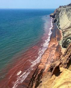 the beach is covered in red algae and brown sand as it sits next to the ocean