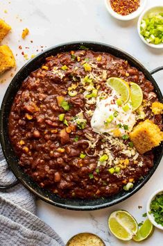 a skillet filled with beans, cornbreads and sour cream on a white table