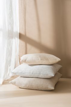 three pillows stacked on top of each other in front of a window