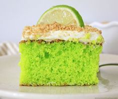 a slice of lime cake on a white plate with a lime wedge and crumbs