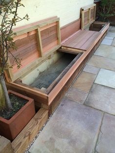 a wooden bench sitting next to a tree on top of a stone floored patio