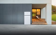 a white refrigerator sitting in the middle of a room next to a wooden floor and stairs