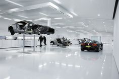 several cars are on display in a showroom with people looking at them and one car is upside down