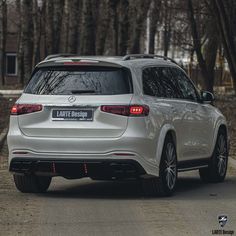 the rear end of a white suv parked in front of trees