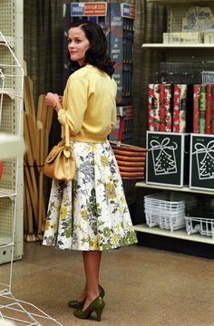 a woman in a store looking at items on the shelves and holding a handbag