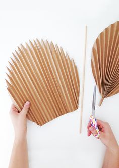 a person holding a pair of scissors next to a paper fan