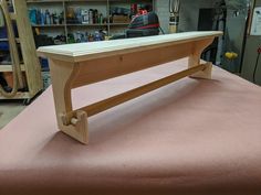 a wooden bench sitting on top of a pink tablecloth covered floor next to shelves