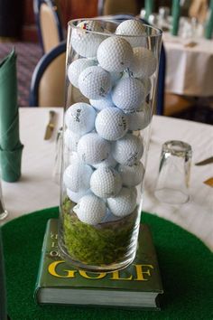 a glass vase filled with golf balls on top of a green tablecloth covered table