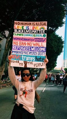 a woman holding up a sign that says no human is illegal