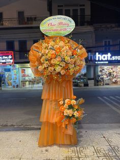 an orange flower arrangement is on the side of the road in front of a store