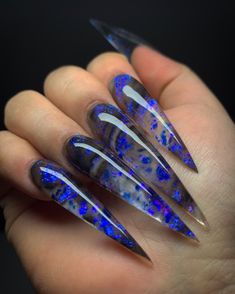 someone is holding their nails with blue and black designs on them