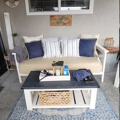 a couch sitting on top of a blue rug in front of a white coffee table