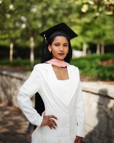 a woman in a graduation cap and gown posing for a photo with her hands on her hips