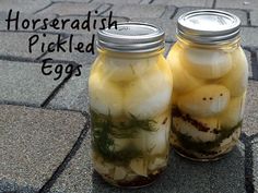 two jars filled with pickled eggs sitting on the ground