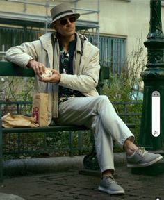 a man sitting on a green bench next to a lamp post