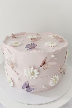 a pink cake with white flowers and butterflies on it