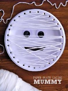 a paper plate that has been made to look like a face with string wrapped around it