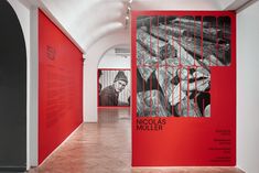 an art gallery with red walls and black and white artwork on the wall, including posters