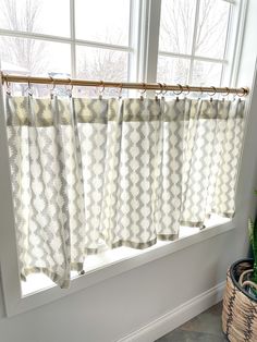 a window with some curtains and a plant in front of it on the windowsill